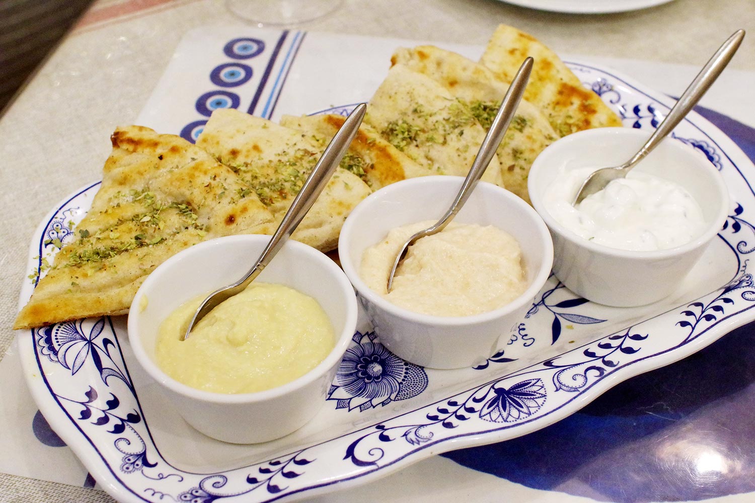 前菜盛り合わせは、ザジキ（ギリシャヨーグルトのディップ）、タラモサラダ、フムス（ひよこ豆のペースト）の3点と、ピタ（平焼きパン）のセット。